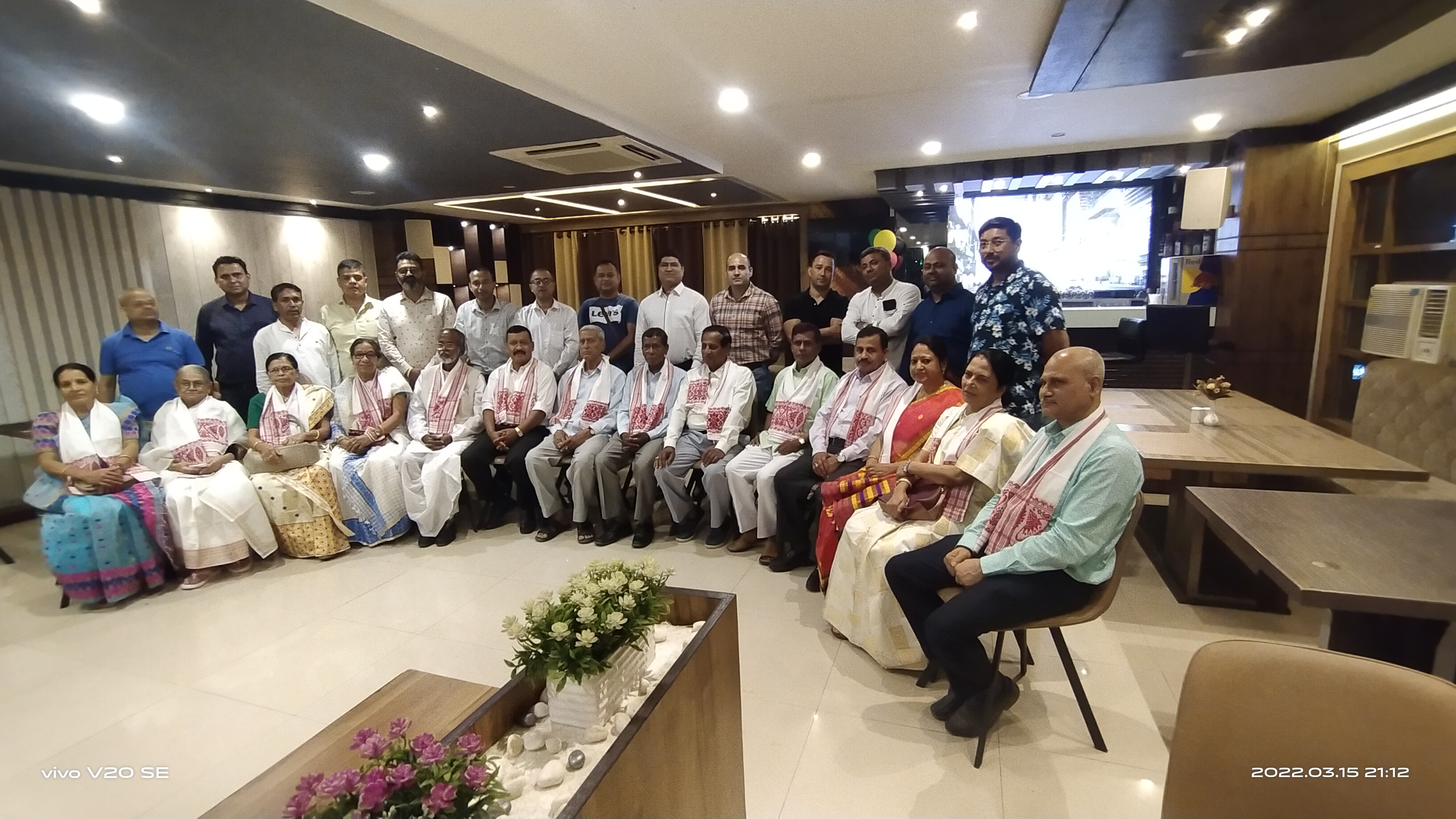 Large group of alumni and organizers posing indoors during a formal reunion or association meeting.